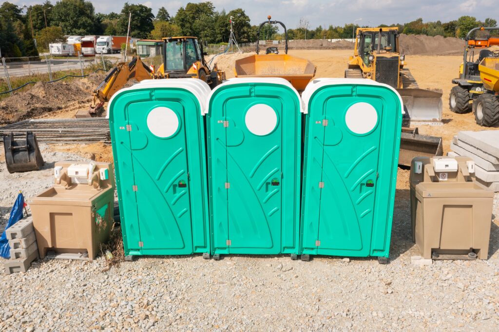 Construction portable restroom positioned away from the main work zone, demonstrating how strategic placement helps prevent avoidable construction delays.